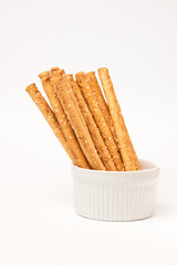 Classic crispy bread sticks grissini with sesame seeds in white form. Traditional Italian pastry breadsticks on white background with copy space