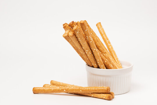 Classic crispy bread sticks grissini with sesame seeds in white form. Traditional Italian pastry breadsticks on white background with copy space