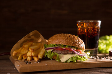 American snack with big burger and glass cola on wooden table