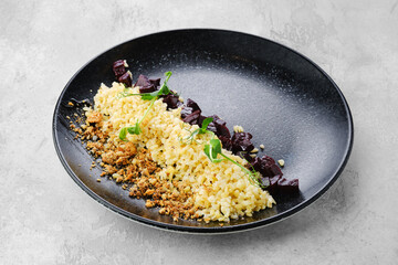 Garnish to the main dish - boiled pearl barley, fried beet and bread crumbs