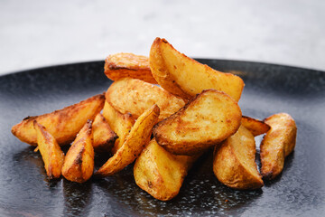 Slices of potato wedges fried in oil, closeup view