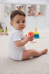 Cute baby boy playing with toy on floor at home