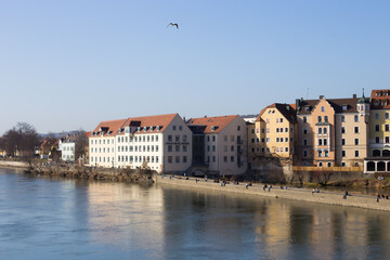 Fototapeta premium Regensburg, Germany - February, 25th 2021: People enjoying spring by the river Danube in Regensburg city center. High quality photo