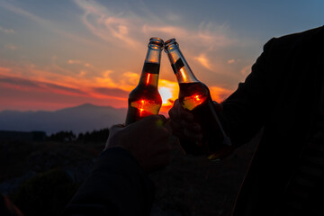 cheering toast beverage alcoholic drink bottles in beautiful evening dark and moody sunset...