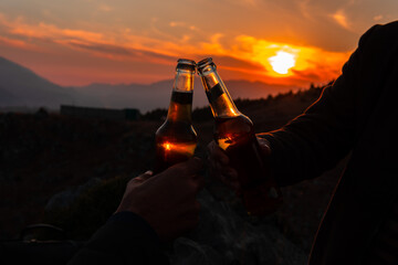 cheering toast beverage alcoholic drink bottles in beautiful evening dark and moody sunset...