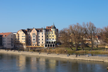 Fototapeta na wymiar Regensburg, Germany - February, 25th 2021: People enjoying spring by the river Danube in Regensburg city center. High quality photo