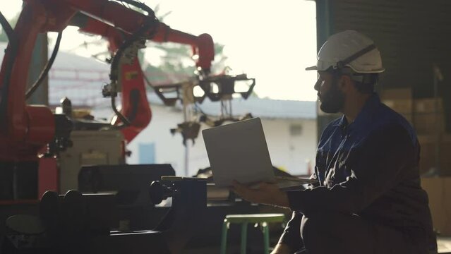 Automation Engineer Uses Laptop for Programming and Testing Robotic Arm. New Era in Automatic Manufacturing Industry.