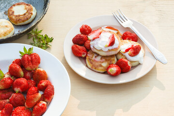 Cheesecakes with strawberries and sour cream. Breakfast in nature. Traditional Russian and Ukrainian dish.
