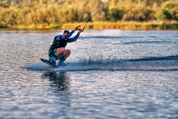A man wakeboarding on a lake on summer day in a life  jacket. Soft focus. Action blur.