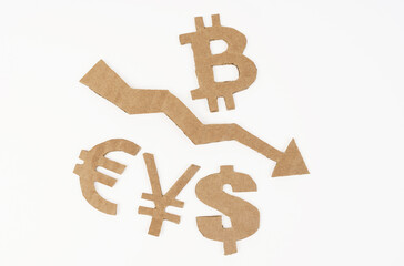 On a white surface, an arrow pointing down and symbols of bitcoin, dollar, euro, yen