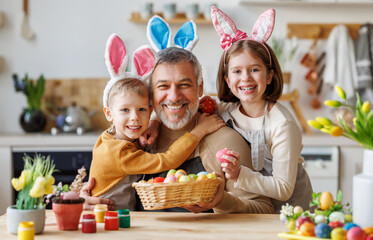 Happy family grandfather and cute grandchildren with Easter basket full of painted colorful eggs