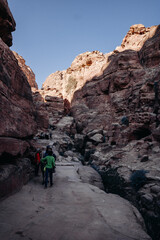 Ruins of the ancient city of Petra in Jordan. Red sandstone mountains on a clear day. Caves in the rock. Tourists in Petra. Colorful photos.