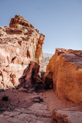 Fototapeta premium Ruins of the ancient city of Petra in Jordan. Red sandstone mountains on a clear day. Caves in the rock. Landscape. Colorful photos.