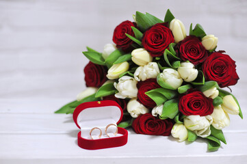 Bouquet of fresh red roses , cream tulips with green leaves  and wedding rings in the red gift box. Marriage proposal photo .Free space for writing text