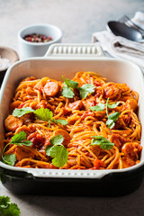 Baked spaghetti pasta with sausages in tomato sauce in oven dish.