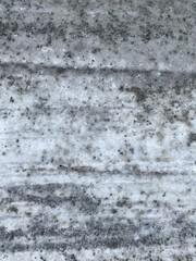 A dirt road covered in snow and ice with scrapes from a plow truck 