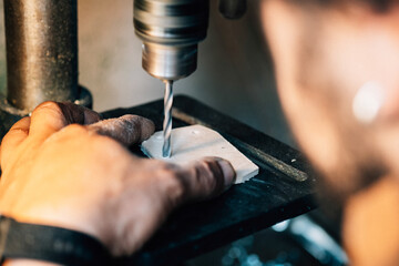 An Anonymous Carpenter Working With Drilling Press Machine. 
Close up photo of man hands drilling hole in wooden plank using an electric drill in his workshop.