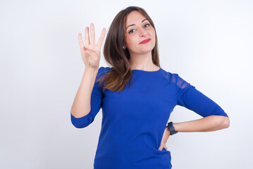 Young arab woman wearing blue dress over white backgtound showing and pointing up with fingers number four while smiling confident and happy.