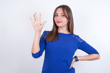 Obraz na płótnie Canvas Young arab woman wearing blue dress over white backgtound showing and pointing up with fingers number five while smiling confident and happy.