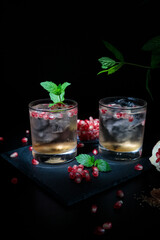 Two summer cocktails with pomegranate and mint on a black background