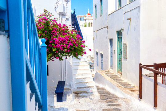 Fototapeta Mykonos old town cozy narrow street with blue staircases, white houses and bougainvillea flower. Mykonos island, Greece