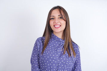 Obraz premium Young arab woman wearing polka-dot clothes over white backgtound with happy and funny face smiling and showing tongue.