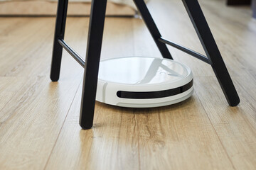 Robot vacuum cleaner on laminate wood floor with chair or table. Robotic automatic cleaner problem....