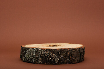 wooden podium on brown background, sawn with bark, eco scene for presentation of beauty products