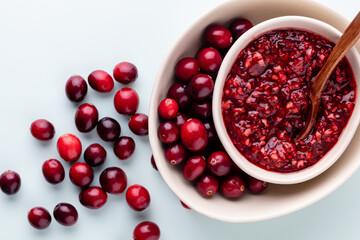 Cranberries in white bowl on pastel background.