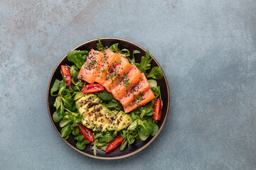 Salmon fish fillet with fresh salad, avocado top view.