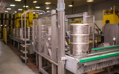 Brewery, bottling beer on aluminum kegs on conveyor lines. Industrial work, automated modern food and beverage production.