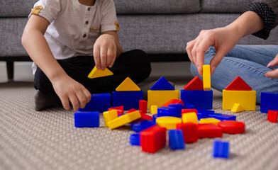 a close-up of a mother and child playing a multi-colored constructor. Early development of the child