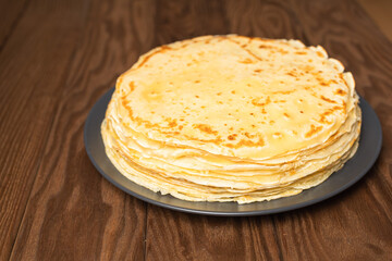 Pancake on the black plate on wooden table. Top view