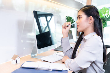 Beautiful Asian businesswoman working in front of her computer in the office with a good atmosphere She has a contemplative attitude about finances. that she must manage to finish