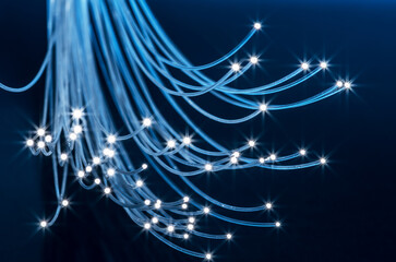Bundle of optical fibers with lights in the ends. Blue background.