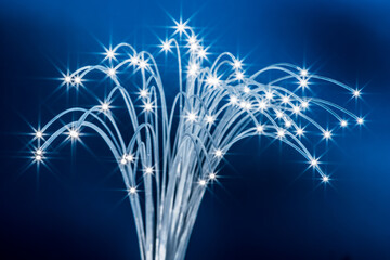 Bundle of optical fibers with lights in the ends. Blue background.