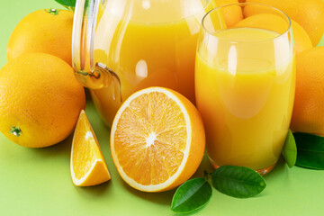 Yellow orange fruits and fresh orange juice isolated on green background. Close-up.