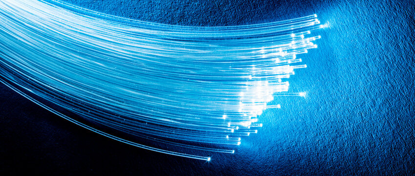 Bundle of optical fibers with lights in the ends. Blue background.