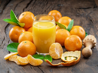 Orange tangerine fruits and glass of fresh tangerine juice on dark wooden background. Top view.