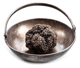 Black winter truffle in the old-fashioned tin bowl isolated on white background.