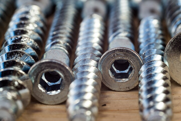 Construction abstraction. Industrial education. Hardware, screws, nails, for metal, for wood, for drywall. Bits, P2, P1, PZ2, PZ1. The screw is screwed into a wooden block. Screw confirmation.