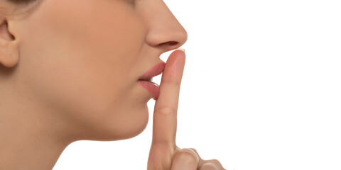 Obraz premium close up profile of young woman holding finger on lips on a white