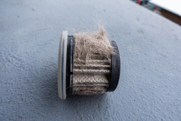 Household handheld vacuum cleaner filter clogging up with dust, mite, hair, and animal fur after an...