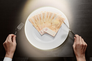 Money on a plate with a fork and knife. Euro banknotes. Wealth and the greed of cash. Business.