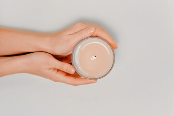 Female hands with scented candle and flowers. Aromatherapy and spa