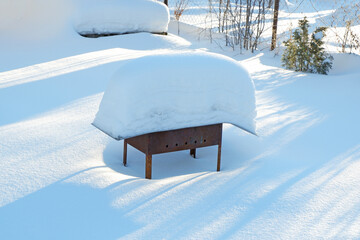 the metal grill stands in the snow
