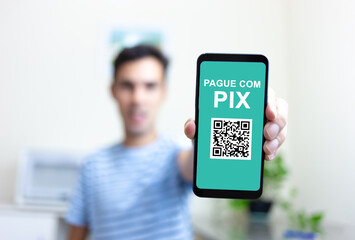 Man holding Smartphone and making payment via PIX.  PIX is a new electronic payment system in...