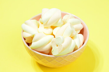 apricot and strawberry marshmallows in pink bowl on yellow background, close-up