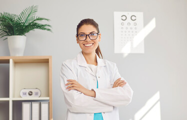 Portrait of happy young Caucasian female optician in white medical uniform pose in optics salon. Smiling woman doctor in private clinic or hospital. Eyesight correction. Healthcare, sight problem. - obrazy, fototapety, plakaty