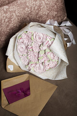 A bouquet of marshmallows. Zephyr flowers. Packed in craft paper. Next to it is a greeting card in an envelope. Close-up.